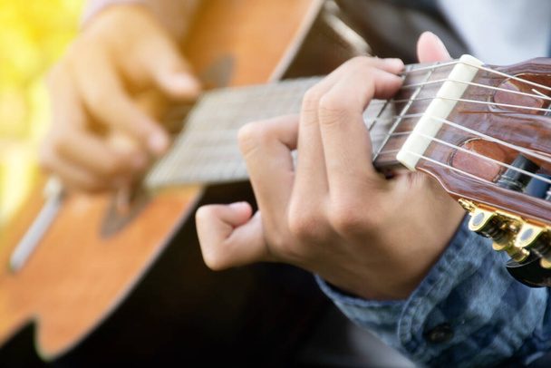 Yakın çekim el ve parmaklar akustik gitar, eğlence aktivitesi, hobi ve serbest stil çalmayı seven insanların popüler enstrümanları. - Fotoğraf, Görsel