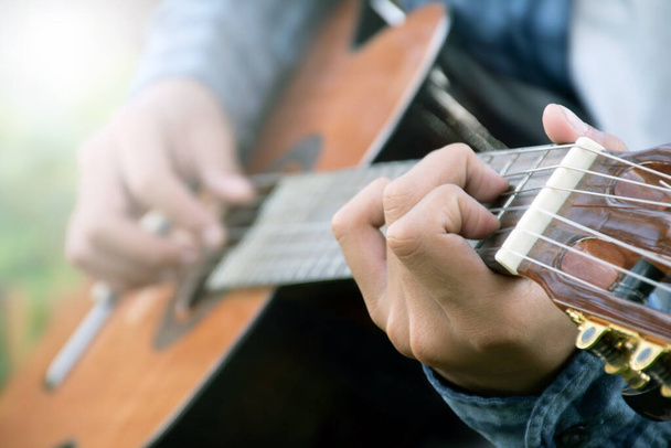 close-up hand en vingers spelen akoestische gitaar, recreatieve activiteit, hobby en freestyle van mensen die graag populaire instrumenten bespelen. - Foto, afbeelding