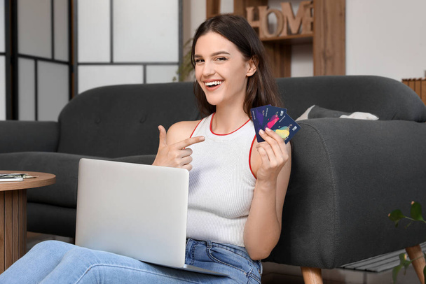 Молода жінка з кредитними картками і ноутбуком вдома - Фото, зображення