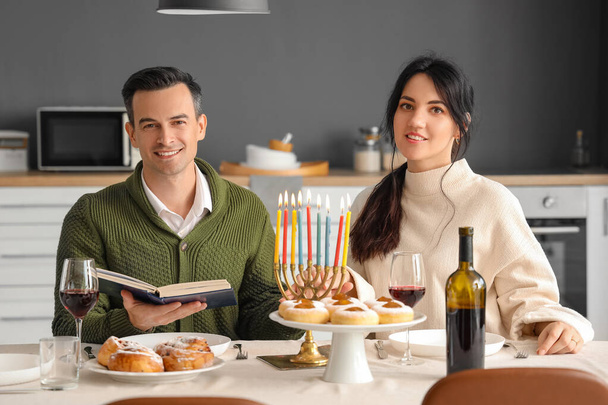 Jovem casal celebrando Hanukkah com Torá na cozinha - Foto, Imagem