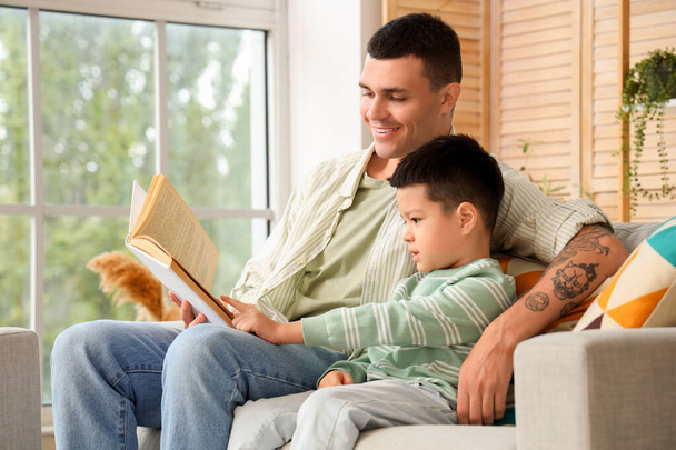 Jovem com seu filhinho lendo livro em casa - Foto, Imagem