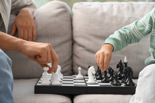 Młody mężczyzna ze swoim synkiem gra w szachy w domu, zbliżenie - Zdjęcie, obraz