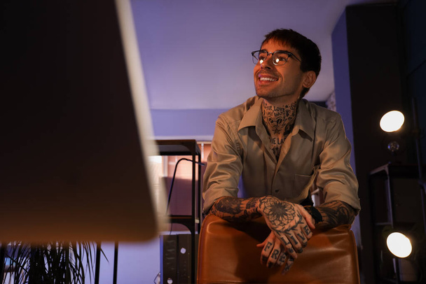 Молодой татуированный человек, работающий ночью в офисе - Фото, изображение