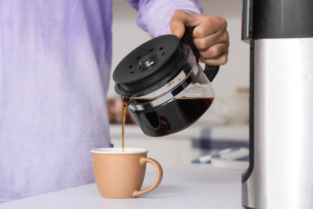 man gieten hete espresso van koffiepot in kopje, close-up - Foto, afbeelding