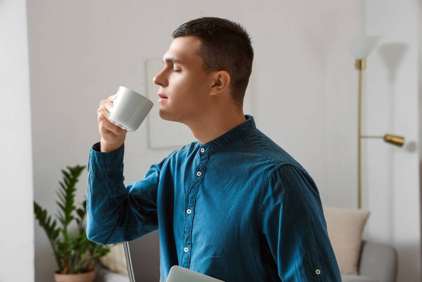 schöner junger Mann, der zu Hause Kaffee trinkt, Nahaufnahme - Foto, Bild