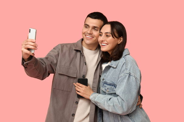 幸せな若いカップルは,ピンクの背景にセルフィーを取る - 写真・画像