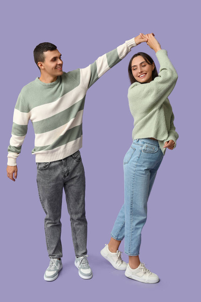 Feliz joven pareja bailando juntos sobre fondo lila - Foto, imagen