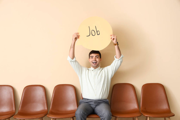 Podnikatel držící řečovou bublinu se slovem JOB u béžové stěny - Fotografie, Obrázek