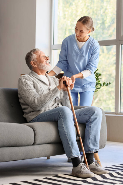 Idősebb férfi bottal és ápolónővel otthon - Fotó, kép