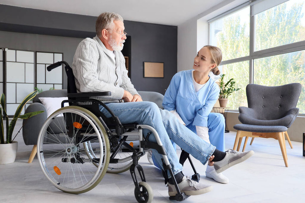 Senior man in rolstoel met verpleegster thuis - Foto, afbeelding