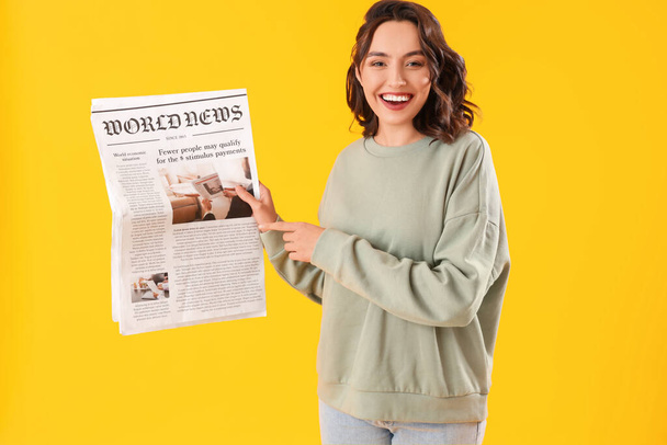 Mujer joven con periódico sobre fondo amarillo - Foto, imagen