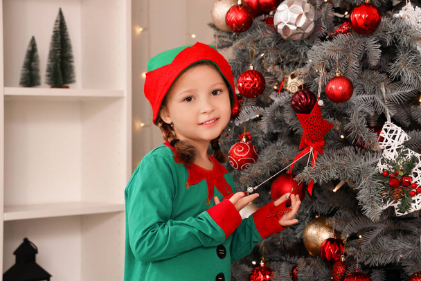 Schattig klein meisje in elf kostuum versieren kerstboom thuis - Foto, afbeelding