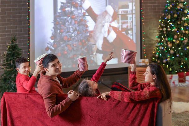 Famille heureuse avec pop-corn regarder film de Noël sur l'écran du projecteur à la maison, vue arrière - Photo, image