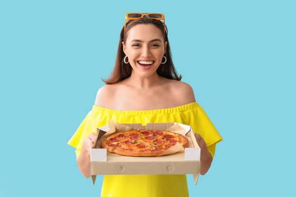 Onnellinen nuori nainen tilalla pahvilaatikko maukas pizza sinisellä pohjalla - Valokuva, kuva