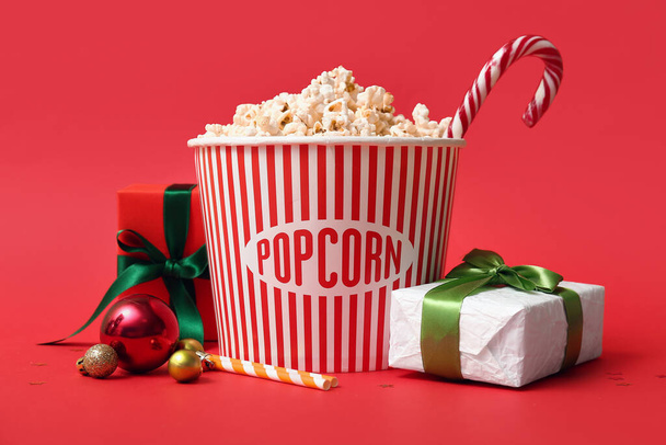 Seau de pop-corn avec cadeaux et décor de Noël sur fond rouge - Photo, image