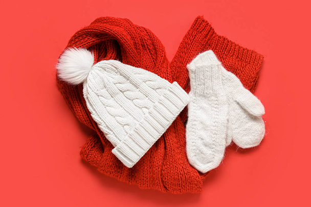 Ζεύγος από λευκά πλεκτά γάντια με ζεστό καπέλο και μαντήλι σε κόκκινο φόντο - Φωτογραφία, εικόνα