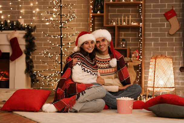 Νεαρό ζευγάρι που βλέπει Χριστουγεννιάτικη ταινία στο σπίτι - Φωτογραφία, εικόνα