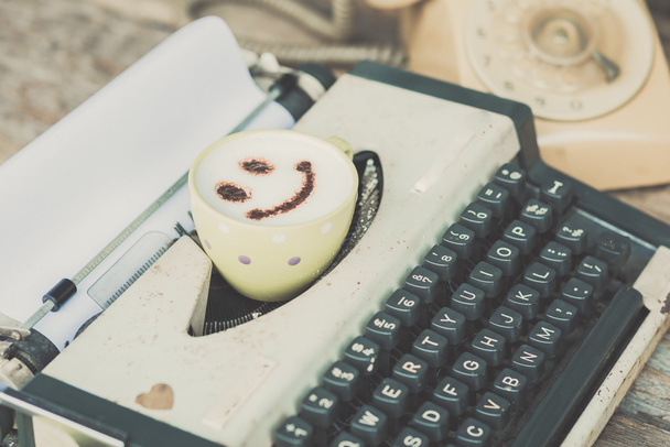 Typewriter with coffee cup and retro phone, sepia tone. - 写真・画像
