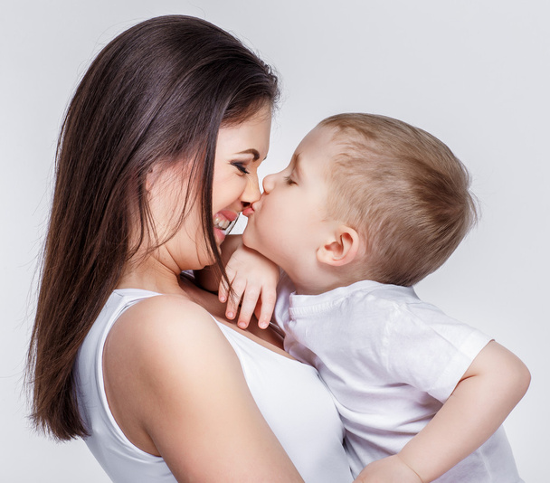 ευτυχισμένη μητέρα με ένα παιδί στο ανοιχτό γκρι φόντο - Φωτογραφία, εικόνα
