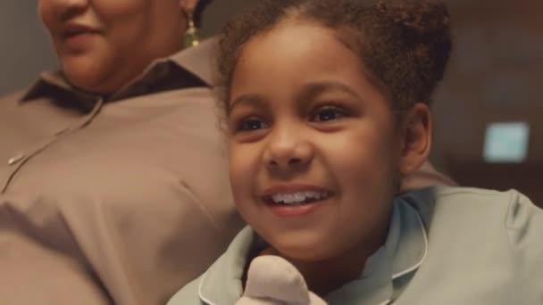 Mittlere Nahaufnahme mit langsamem Genuss eines kleinen afroamerikanischen Mädchens, das Videospiele auf der Konsole spielt, während es am Wochenende bei Omas zu Hause bleibt - Filmmaterial, Video