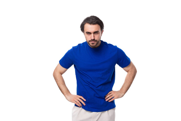 portret van een jonge slimme blanke brunette man met een baard in een blauw t-shirt. - Foto, afbeelding