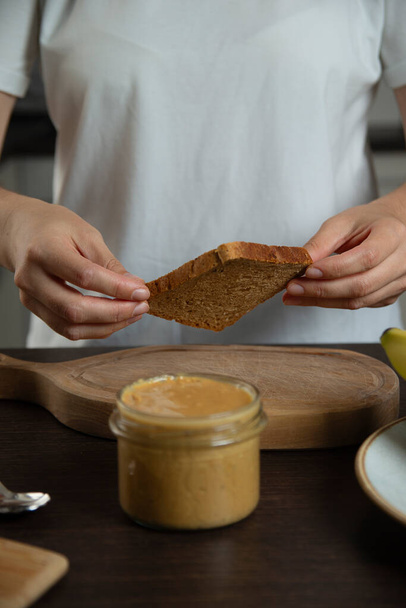 Woman preparing breakfast. Bread with peanut butter. - Photo, Image