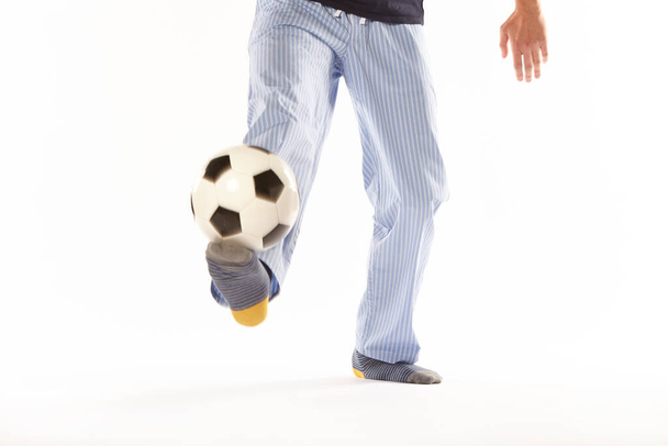 パジャマの若い男がサッカーをしている。足の詳細。ナイトウェア - 写真・画像