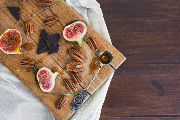 Fresh figs and pekan nuts with honey on a wooden board - 写真・画像