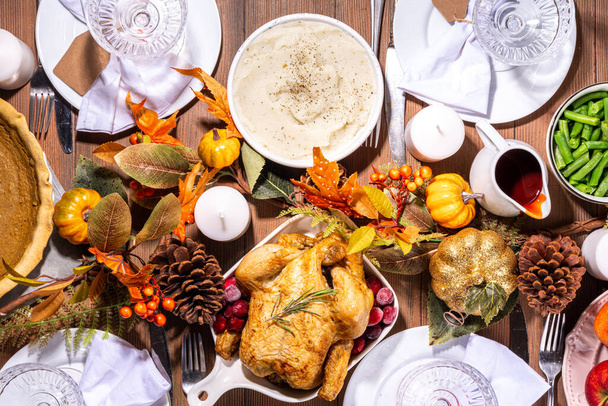 Ajuste de mesa para la cena familiar de Acción de Gracias con platos, cubiertos, vasos, platos tradicionales: pavo o pollo al horno, pastel de calabaza, frutas, puré de papas, judías verdes, fondo de madera - Foto, imagen