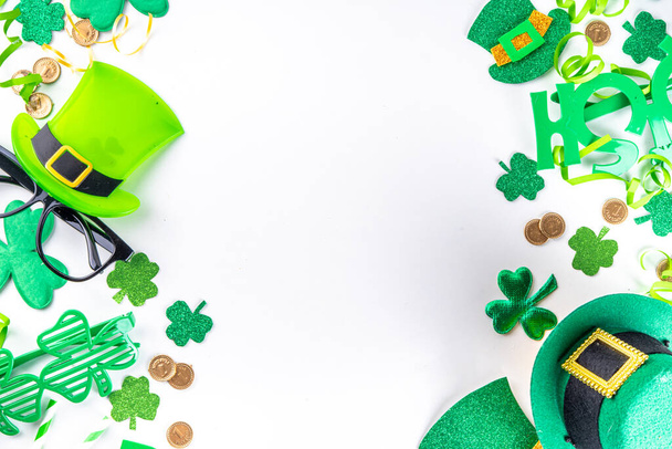 St Patrick holiday flatlay background with shamrock clover leaves, leprechaun hat decor, golden coin, party accessories, symbols of Patrick day - Photo, Image