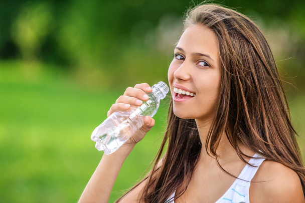 Молодая женщина пьет бутылку воды - Фото, изображение