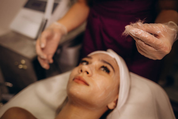 Bir kozmetik uzmanı bir kadına ipeksi yüz ameliyatı yapar. - Fotoğraf, Görsel