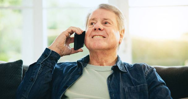 Senior man, gelukkig of telefoongesprek in huis praten of spreken in de woonkamer voor communicatie. Lachen, mobiele of oudere man in gesprek om te ontspannen op de lounge bank of bank in huis alleen. - Foto, afbeelding
