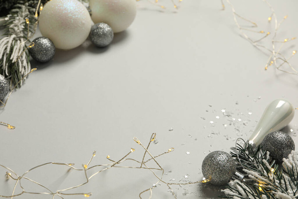 Christmas tree branches, garland and balls on gray background, space for text - Photo, Image