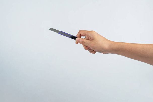 Cuchillo de corte herramienta oficina para papel de corte en la mano sobre fondo blanco - Foto, Imagen