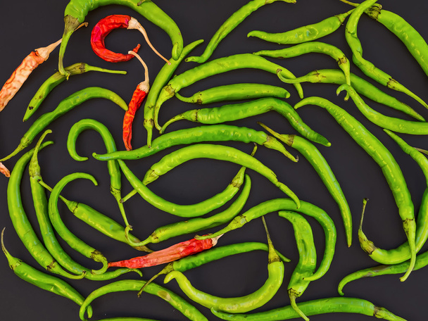 Green and red chili peppers on black - 写真・画像