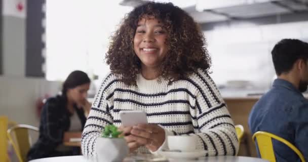 Femme, sourire et utiliser le téléphone dans le café pour les médias sociaux dans le café et se détendre avec bonheur. Africain, portrait et personne au restaurant avec smartphone pour la communication et la connexion Internet. - Séquence, vidéo