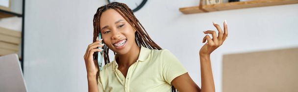 wesoły afrykański amerykański sprzedawca detaliczny kobieta mówi przez telefon i uśmiecha się podczas ciężkiej pracy, sztandar - Zdjęcie, obraz