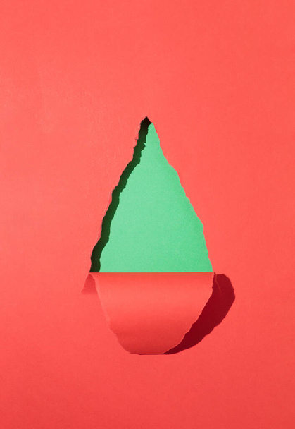 Ένα σχήμα χριστουγεννιάτικου δέντρου από κόκκινο και πράσινο χαρτί. Ελάχιστο χριστουγεννιάτικο φόντο με αντίγραφο χώρου. - Φωτογραφία, εικόνα