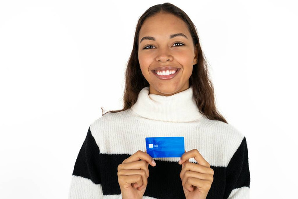 Foto di giovane bella donna che indossa maglione a righe su sfondo bianco sorriso positivo tenere salario della carta di credito - Foto, immagini