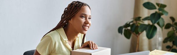 lustige afrikanisch-amerikanische Frau hält Scanner neben Schachtel während der Arbeit, Lieferkonzept, Banner - Foto, Bild