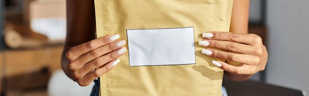 bijgesneden beeld van Afrikaans-Amerikaanse vrouwelijke verkoper holding post pakketten, levering concept, banner - Foto, afbeelding