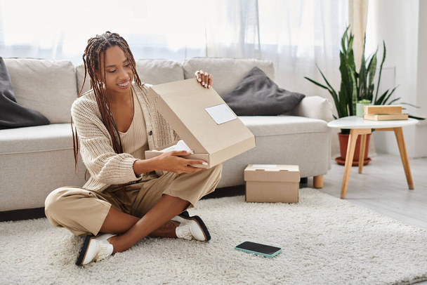 alegre boa aparência afro-americana mulher com aparelho sentado no chão e unboxing seu pacote - Foto, Imagem