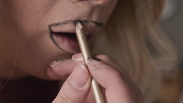 Gros plan de l'homme queer méconnaissable appliquant doublure de lèvre brune à l'extérieur du contour naturel des lèvres tout en faisant glisser le maquillage dans les coulisses - Séquence, vidéo