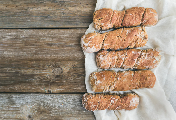 Freshly baked rustic  village bread (baguettes) set on rough woo - Photo, Image