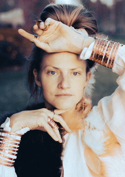 Jovem mulher forte com pele, ornamentos de penas, anéis de cobre dourado e pulseiras - Foto, Imagem