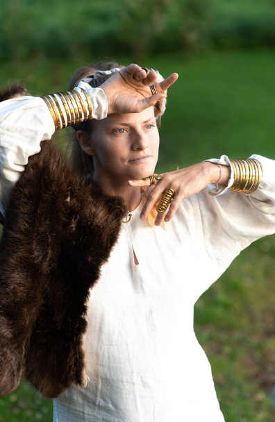 Гармоничная спокойная женщина с мехом, перьями украшения, позолоченные медные кольца и браслеты - Фото, изображение