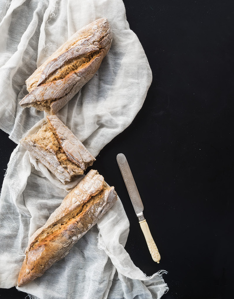 French baguette broken into pieces on a white kitchen towel with - Фото, изображение