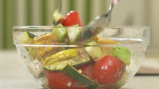 Женщина приправляет свежие овощи и зелень в стеклянную миску для выпечки - Кадры, видео