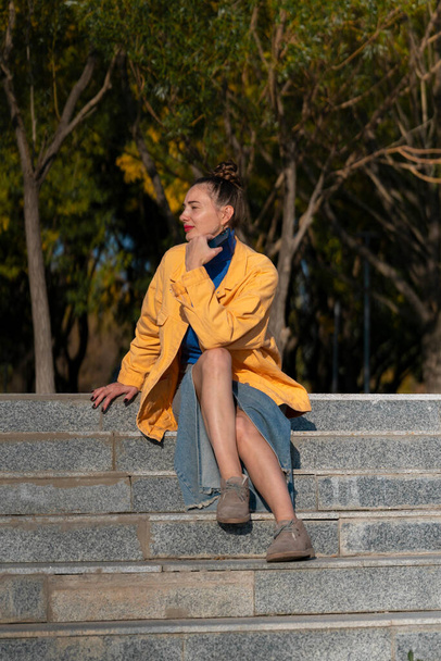 Una giovane donna siede sui gradini della strada. Foto di alta qualità - Foto, immagini